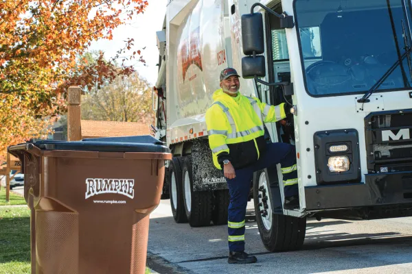 Rumpke Driver Next To Truck And Container