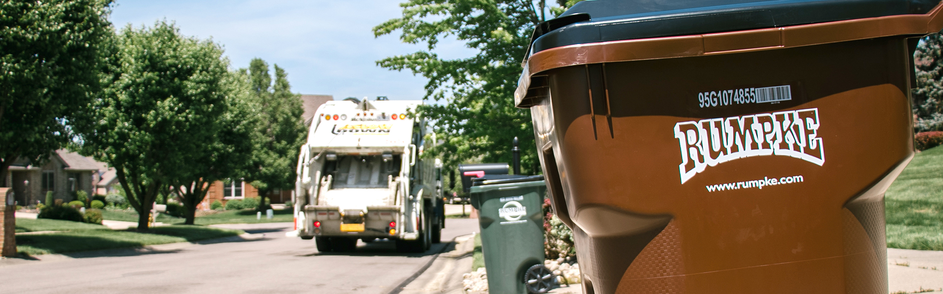 Rumpke Waste pickup truck and trash cart on a residential street